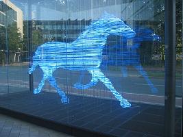 Moderne blaue Lichtskulptur eines galoppierenden Pferdes in einer Glasfassade
